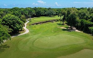 Ein Golfplatz mit gepflegter Spielbahn, Sandbunkern und einem Wasserhindernis.