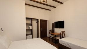 A bedroom with two beds, a desk, a chair, a TV, and a wardrobe. - VillaStarova (Berat)