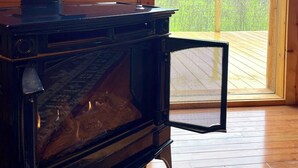 Een houten hutje met een piano, een bordje voor visreizen en uitzicht op een bebost landschap.