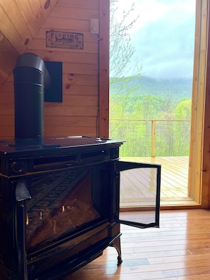 Una cabaña de madera con un piano, un anuncio de excursiones de pesca y vistas a un paisaje boscoso.