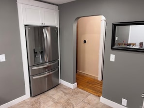 Une cuisine avec un réfrigérateur en acier inoxydable, un plancher en bois et un miroir au mur.