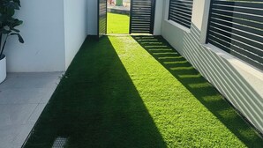 Un edificio moderno con un césped artificial estrecho y verde que conduce a una entrada con portones.