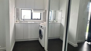 Una cocina compacta con lavadora integrada, una ventana y un espejo grande.