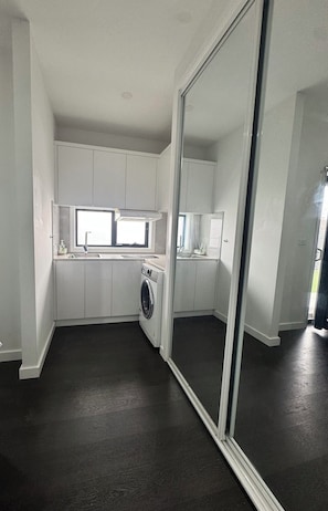 A compact kitchen with a built-in washer, a window, and a large mirror.