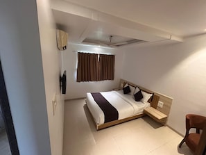 A bedroom with a bed, bedside table, chair, and a ceiling fan.