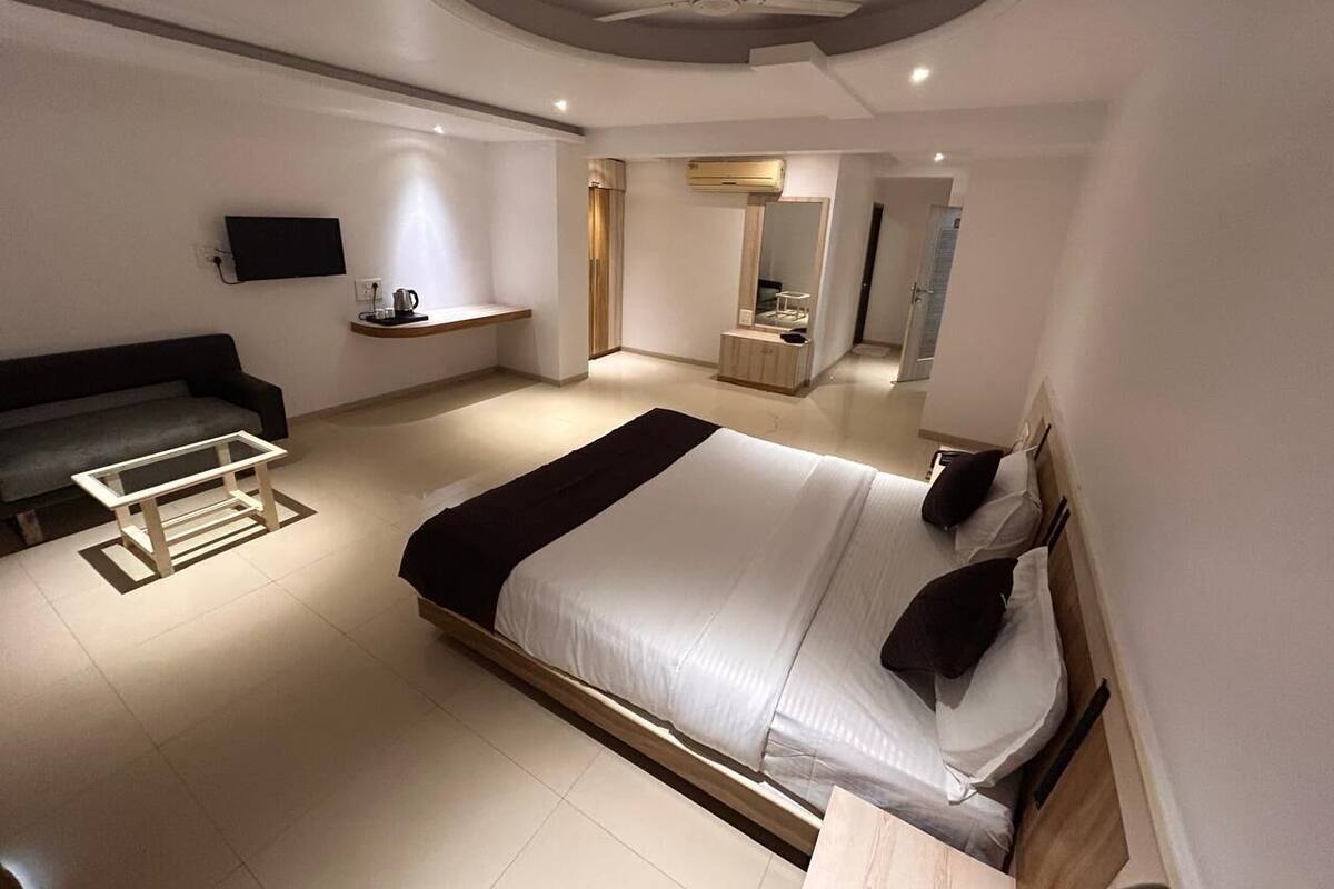 Un dormitorio moderno con una cama grande, un sofá, un televisor y un ventilador de techo.
