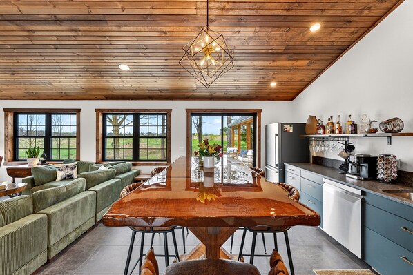 Eine moderne Küche mit Holzboden, großen Fenstern und einem Essbereich mit einem Holztisch.