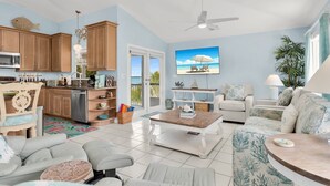 Un amplio espacio de estar con cocina, una mesa de comedor, un sofá y un televisor.