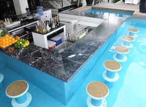 A poolside bar area with a marble countertop, a fruit display, and multiple stools. - TWO BEDROOM PENTHOUSE  (Angeles)
