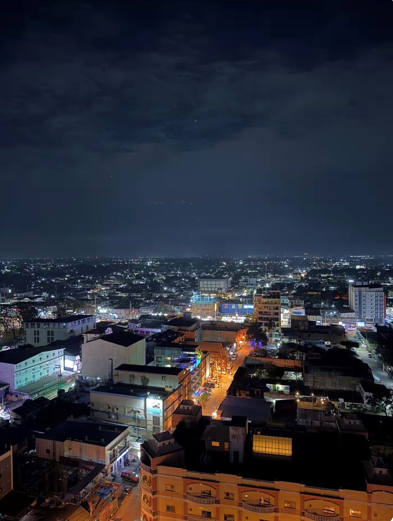 A nighttime cityscape with illuminated buildings and a river.