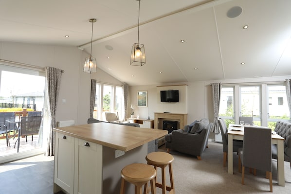 A spacious living area with a kitchen island, dining table, and seating.