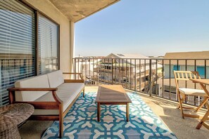 A balcony with a sofa, a small table, and chairs, overlooking a residential area.