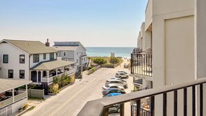 Une rue résidentielle située sur la côte, bordée de maisons, avec une plage et des voitures garées.