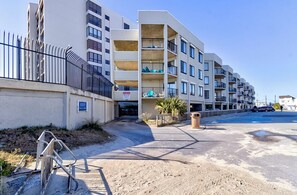 A multi-story residential building with balconies, a gated entrance, and a clear sky.