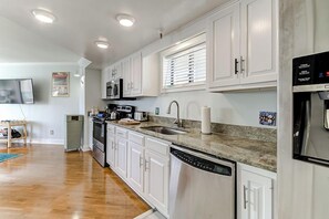 A modern kitchen with white cabinets, stainless steel appliances, and a granite countertop.