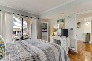 A bedroom with a bed, a desk with a TV, a wardrobe, and a window with blinds.
