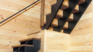 Interior de madera con una escalera, un radiador negro y una pared de madera.