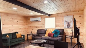 Un interior de madera con un sofá, una mesa y un televisor sobre un trípode.