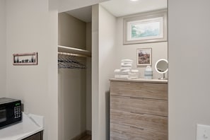 A bathroom with a wooden vanity, a towel stack, a mirror, and a framed picture on the wall. - Sullivan Trail Inn and Suites (Pocono Lake)