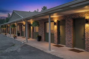 Una hilera de habitaciones de motel con entradas individuales, cada una con un número de puerta y un pequeño porche.