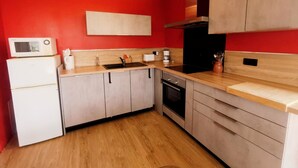 Una cocina compacta con microondas, tostadora, lavabo y estufa.