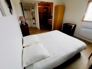 A bedroom with a bed, a wardrobe, a desk, and a bathroom visible through an open door.