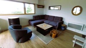 Una sala de estar moderna con un sofá modular, una mesa de centro, un espejo redondo y un radiador.