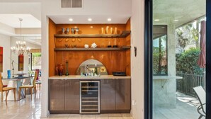 Eine moderne Küche mit integriertem Kühlschrank, einem Essbereich mit Stühlen und Blick ins Freie durch eine Glastür.