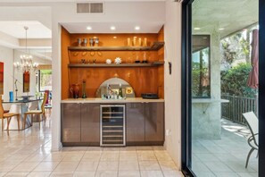 Eine moderne Küche mit integriertem Kühlschrank, einem Essbereich mit Stühlen und Blick ins Freie durch eine Glastür.