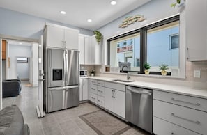 A modern kitchen with stainless steel appliances, a large window, and a view of the outside.