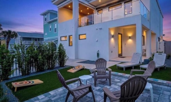 A two-story house with a balcony, outdoor seating area, and a well-maintained lawn.
