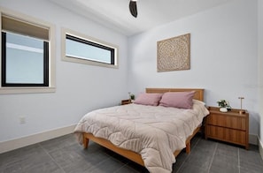 A bedroom with a bed, a nightstand, a wall-mounted decorative piece, and a window.