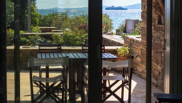 Ein Zimmer mit Meerblick, eine Terrasse mit Tisch und Stühlen sowie eine Steinsäule.