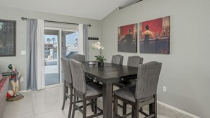 A dining area with a dark wooden table and six chairs, a ceiling fan, and a view through a glass door to an outdoor balcony. - Lakefront retreat w/Private pool- Winter/Mid-Term visitor discount available (Fort Mohave)