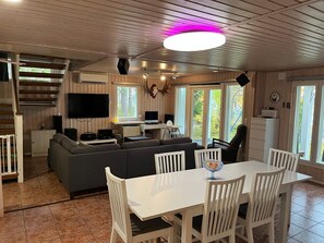 Mökin sisätilat, joihin kuuluu oleskelutila, ruokapöytä ja portaikko.