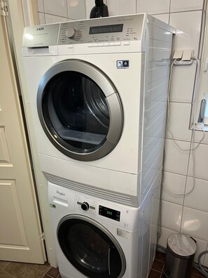 A stacked washer and dryer unit with a control panel, a digital display, and a water inlet hose.