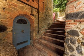 A stone staircase leading to a blue door with a metal ring handle, surrounded by stone walls and a brick archway. - Charming mill nestled in the woods, convenient for visiting all of Tuscany (Colle di Buggiano)