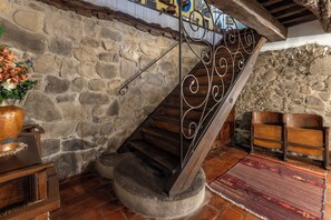 A stone wall, a wooden staircase with metal railings, a wooden chair, and a patterned rug. - Charming mill nestled in the woods, convenient for visiting all of Tuscany (Colle di Buggiano)
