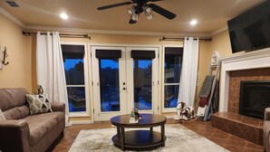 A living room with a brown leather sofa, a coffee table, a fireplace, and a TV. - River House with dock & boat slip, perfect for Alabama & Mississippi game days (Columbus)