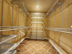 A narrow walk-in closet with metal shelving units and a tiled floor.