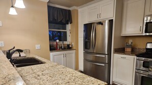 A kitchen with granite countertops, stainless steel appliances, white cabinetry, and pendant lighting. - River House with dock & boat slip, perfect for Alabama & Mississippi game days (Columbus)