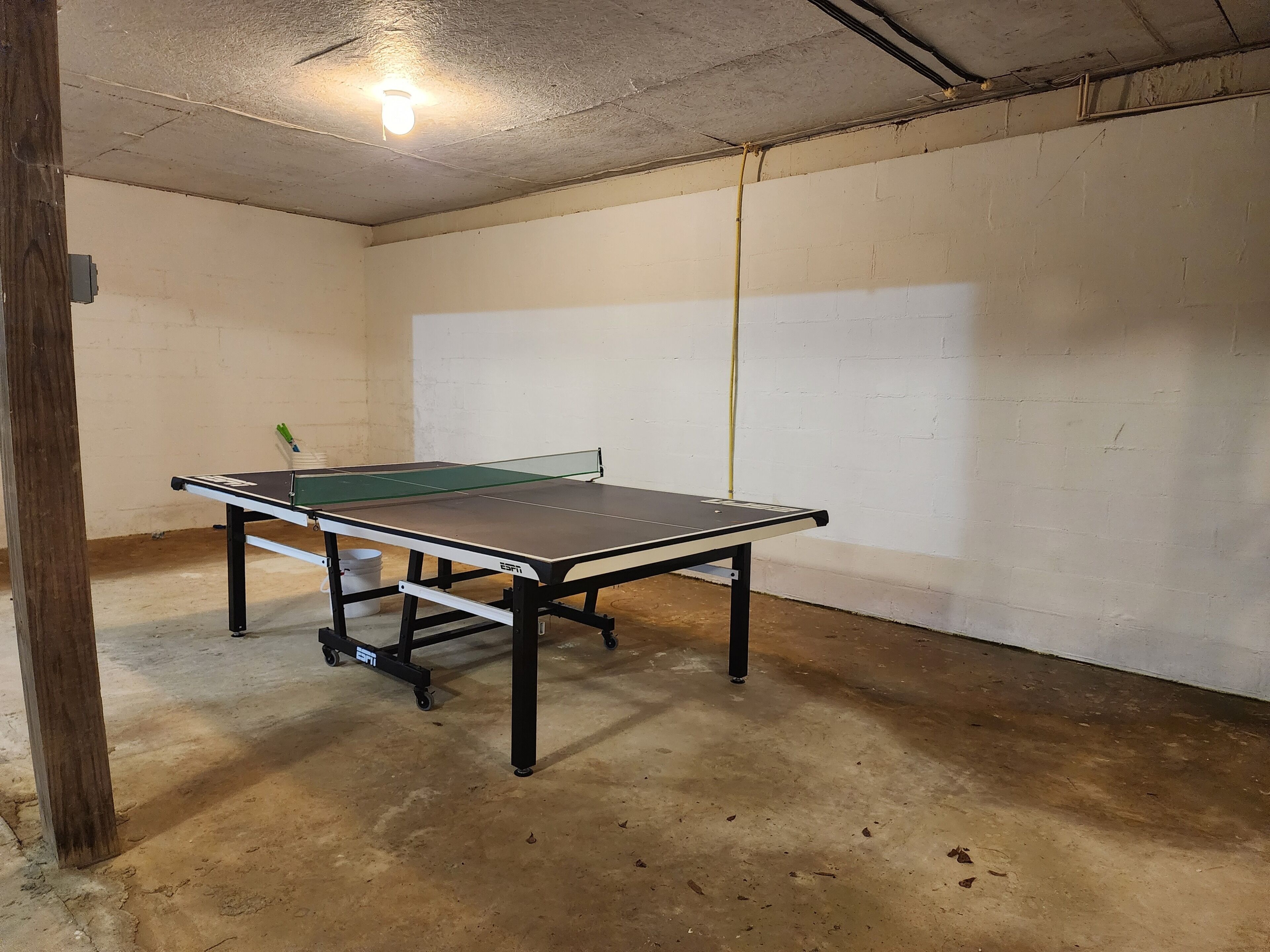 A ping pong table in a room with white brick walls and a concrete floor.