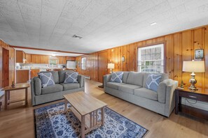 A spacious living room with two sofas, a coffee table, and a wooden floor. - Steps to Colonial Acres Beach Spacious Home (Yarmouth)