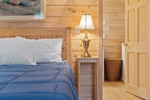 Una habitación de madera con una cama, una lámpara y una puerta.