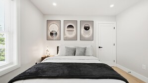 Ein Schlafzimmer mit einem Bett, einem Fenster und drei Wandbildern.