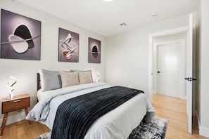 A modern bedroom with a bed, bedside tables, and wall art.