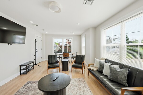 A modern living room with a sofa, chairs, a coffee table, and a TV mounted on the wall.