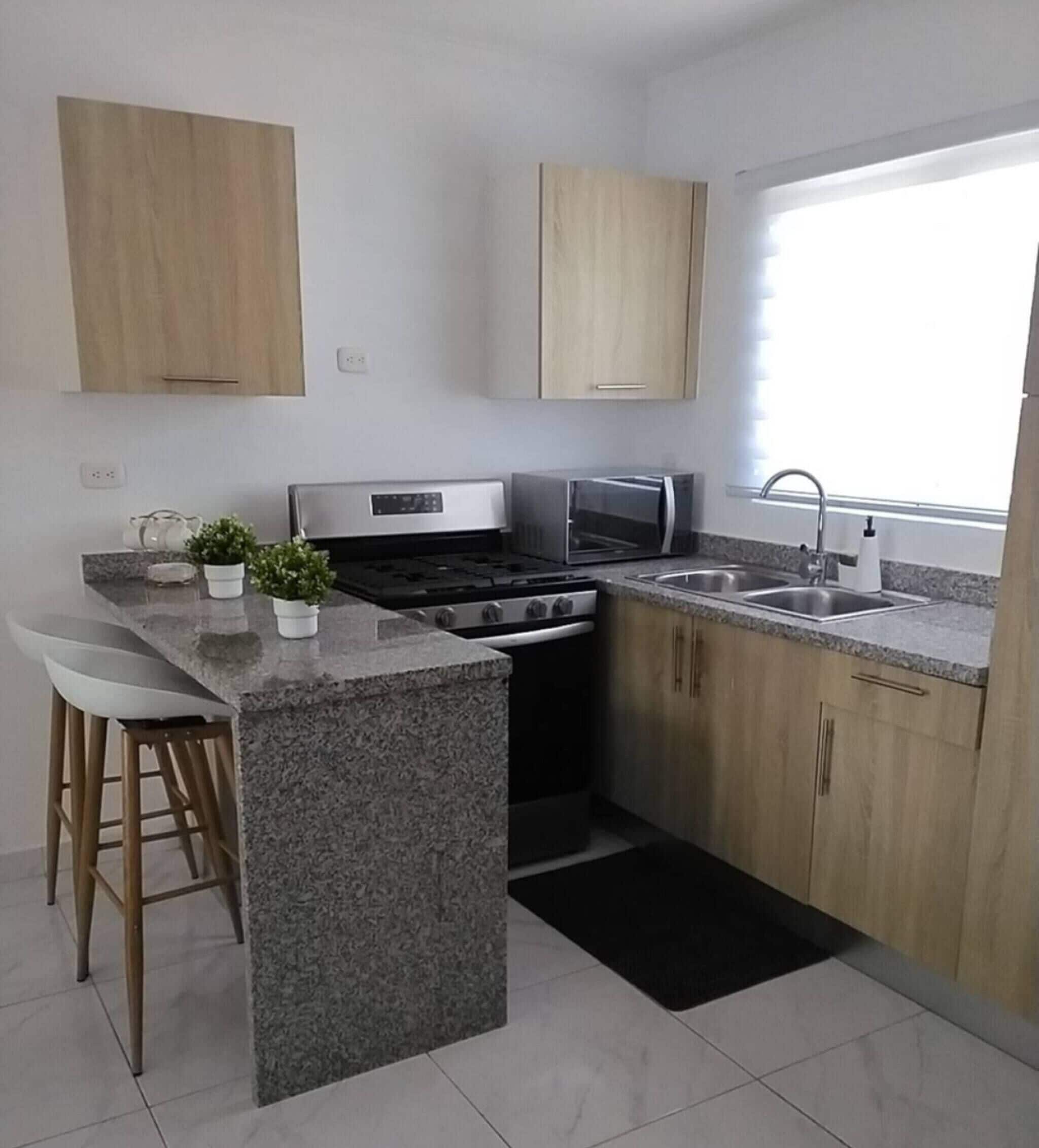 A modern kitchen with granite countertops, a built-in stove, a microwave, and wooden cabinets.