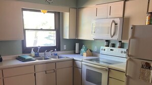 A kitchen with a sink, stove, microwave, and refrigerator. - Rustic recently updated 3-bedroom cabin with AC on Upper Turtle Lake. (Turtle Lake)