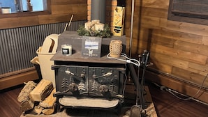 A wood-burning stove with a chimney, a framed picture, and a candle on a brick hearth. - Rustic recently updated 3-bedroom cabin with AC on Upper Turtle Lake. (Turtle Lake)